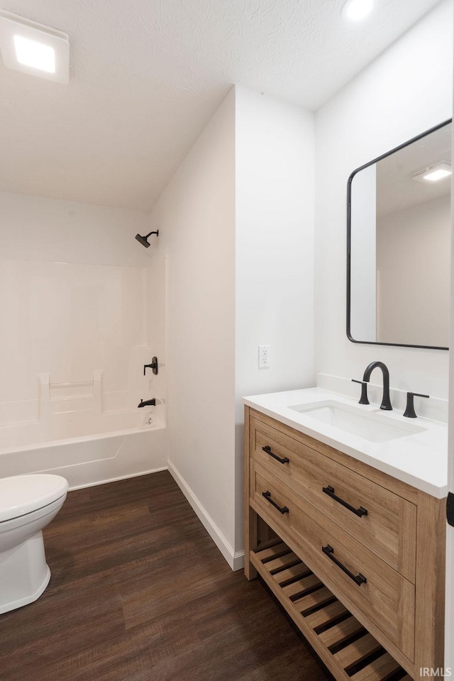 bathroom featuring toilet, shower / tub combination, wood finished floors, vanity, and baseboards