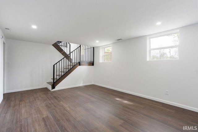 below grade area featuring stairway, baseboards, visible vents, and wood finished floors
