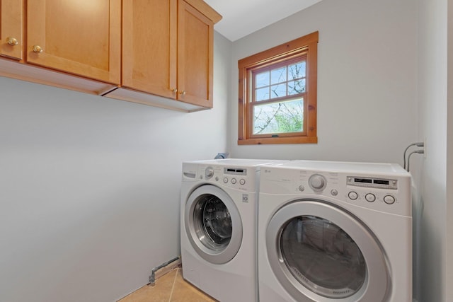 clothes washing area featuring separate washer and dryer, cabinet space, and light tile patterned floors