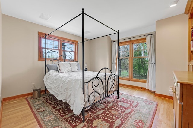 bedroom featuring multiple windows, light wood-style floors, and baseboards