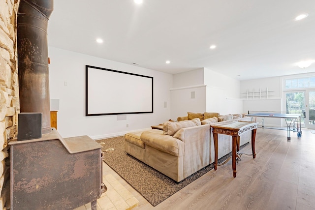 cinema featuring a wood stove, baseboards, light wood-type flooring, and recessed lighting