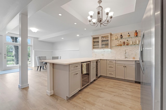 kitchen featuring wine cooler, light wood-style flooring, a peninsula, backsplash, and stainless steel appliances