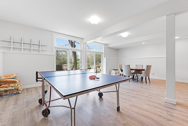 rec room with baseboards, light wood finished floors, and beam ceiling