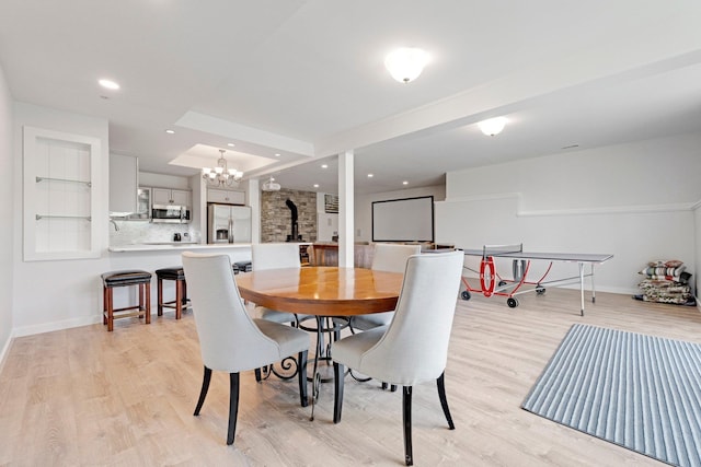 dining room featuring baseboards, light wood-type flooring, a notable chandelier, and recessed lighting