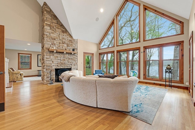 living area with a fireplace, baseboards, high vaulted ceiling, and light wood-style floors