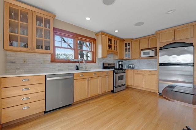 kitchen with light brown cabinetry, light wood finished floors, a sink, light countertops, and appliances with stainless steel finishes