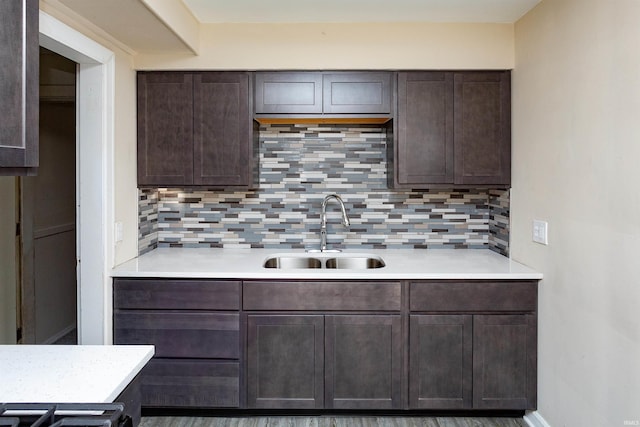 kitchen with light countertops, decorative backsplash, dark brown cabinets, and a sink