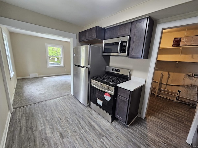 kitchen featuring stainless steel appliances, baseboards, visible vents, wood finished floors, and light countertops