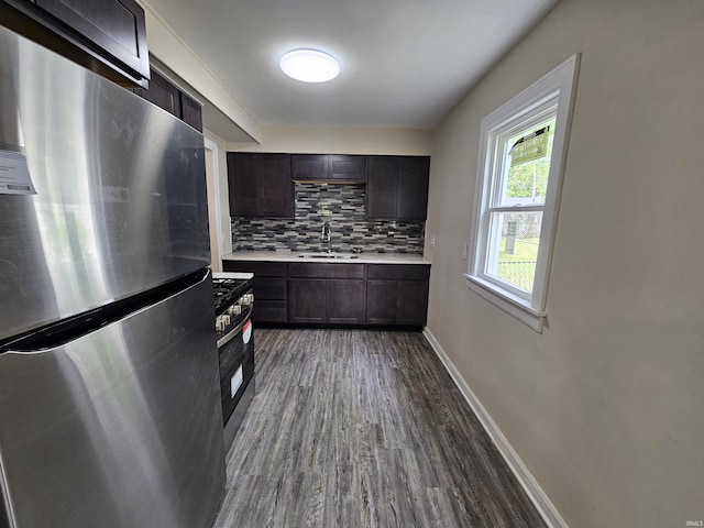 kitchen featuring a sink, stainless steel appliances, light countertops, tasteful backsplash, and dark wood-style floors