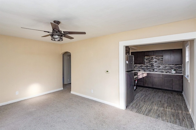 interior space with ceiling fan, dark colored carpet, baseboards, and arched walkways