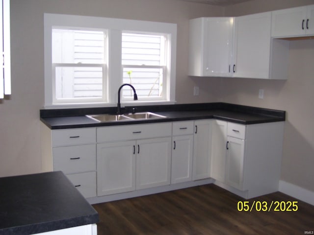 kitchen featuring a sink, dark countertops, dark wood-style flooring, and white cabinetry