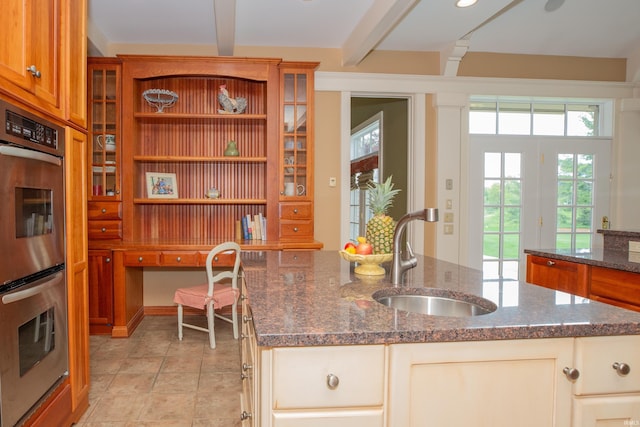 13 Rolling Ridge Ct, Jasper, IN 47546 - kitchen with brown cabinets, a sink, dark stone counters, stainless steel double oven, and a center island with sink