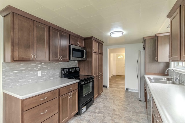 306 S Main St, Topeka, IN 46571 - kitchen featuring a sink, baseboards, light countertops, appliances with stainless steel finishes, and decorative backsplash