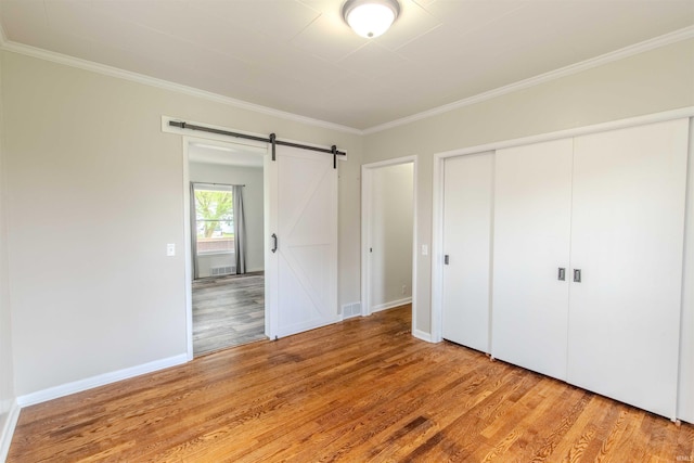 306 S Main St, Topeka, IN 46571 - unfurnished bedroom featuring light wood-style flooring, a closet, crown molding, visible vents, and a barn door