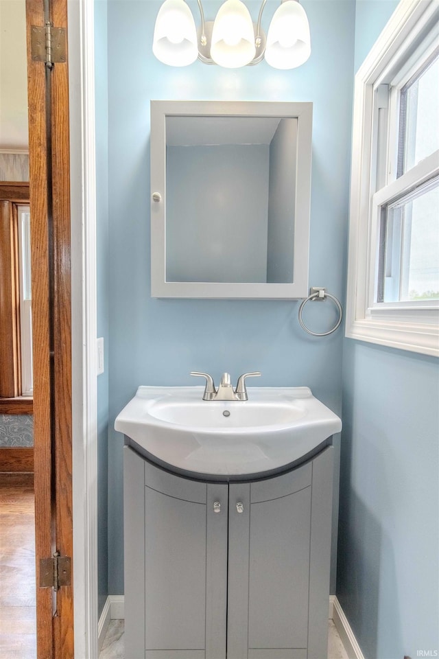 306 S Main St, Topeka, IN 46571 - bathroom with baseboards, vanity, and a notable chandelier