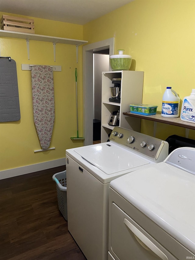 washroom featuring laundry area, washer and clothes dryer, dark wood-style flooring, baseboards, and an AC wall unit
