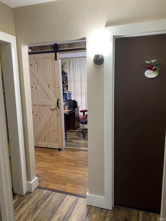 hallway with a barn door and wood finished floors