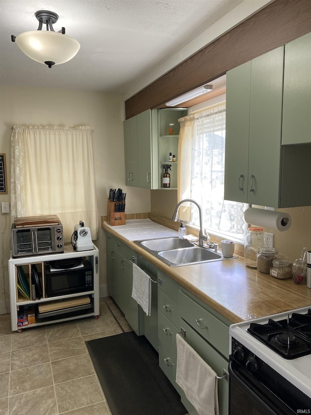 kitchen featuring a sink, a toaster, green cabinets, light countertops, and gas stove