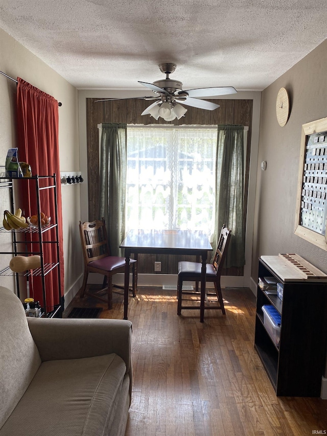 sitting room featuring dark wood-style flooring, a textured ceiling, and a ceiling fan