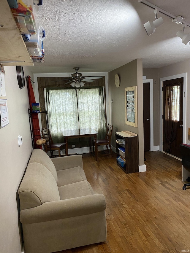 living area featuring ceiling fan, a textured ceiling, track lighting, and wood finished floors