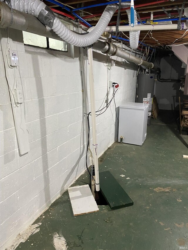 unfinished basement with fridge, water heater, and concrete block wall