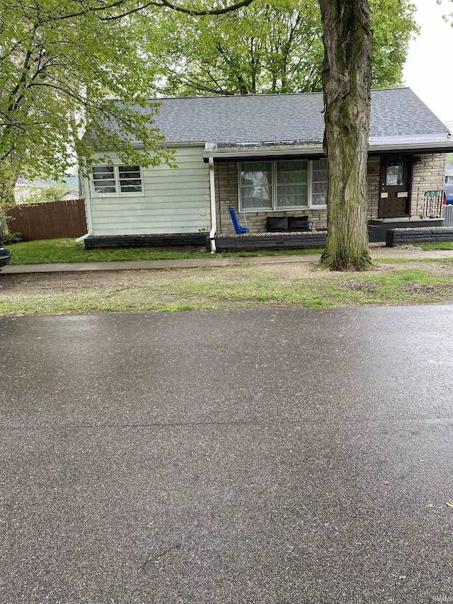 view of front of home with roof with shingles and fence
