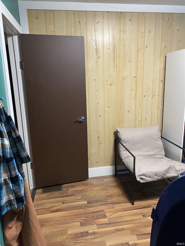 bedroom featuring wood walls, baseboards, and light wood-style floors