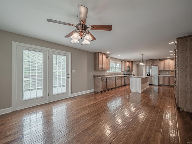 kitchen featuring stainless steel appliances, baseboards, dark wood finished floors, ceiling fan, and a kitchen island