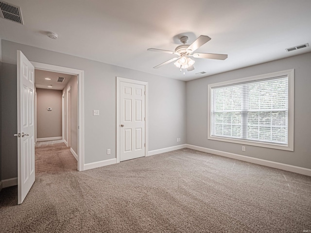 unfurnished bedroom featuring baseboards, ceiling fan, visible vents, and carpet