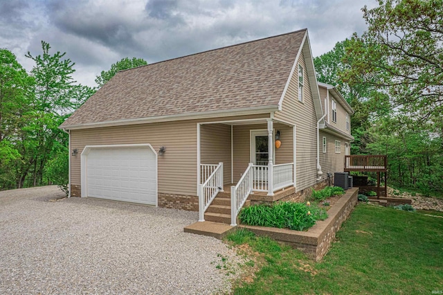 view of front facade with an attached garage, driveway, roof with shingles, and central AC