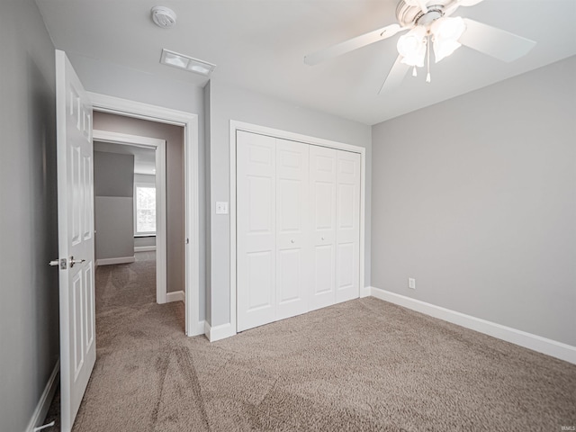 unfurnished bedroom with a closet, visible vents, ceiling fan, carpet floors, and baseboards