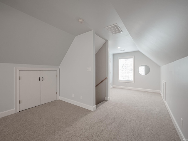 additional living space featuring vaulted ceiling, carpet flooring, baseboards, and visible vents