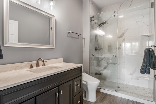 full bath featuring toilet, a marble finish shower, wood finished floors, and vanity