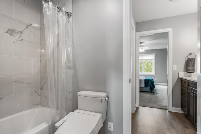 ensuite bathroom with toilet, wood finished floors, vanity, a ceiling fan, and shower / tub combo