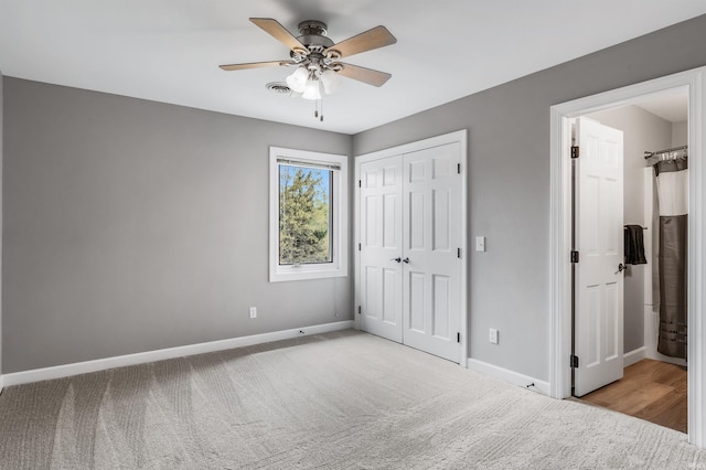 unfurnished bedroom with a ceiling fan, a closet, ensuite bathroom, baseboards, and light carpet