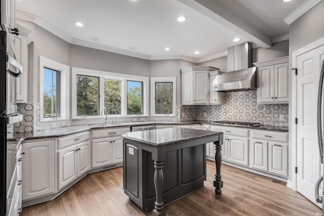 kitchen featuring crown molding, wall chimney exhaust hood, stainless steel appliances, and a sink