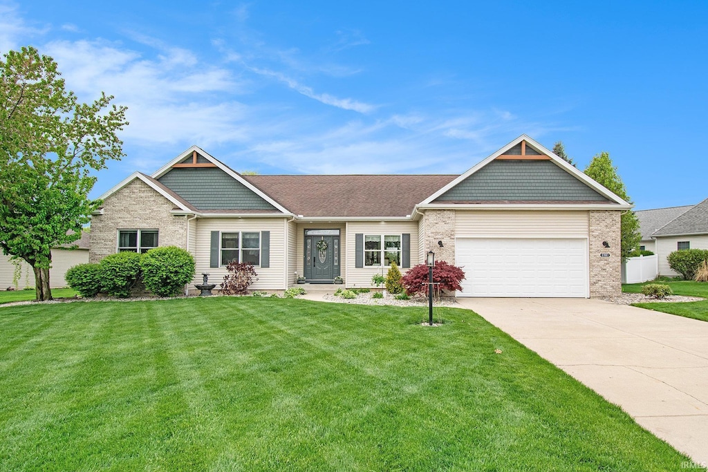 view of front of house featuring an attached garage, concrete driveway, brick siding, and a front lawn