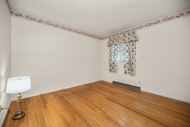 spare room with wood finished floors, baseboards, and baseboard heating