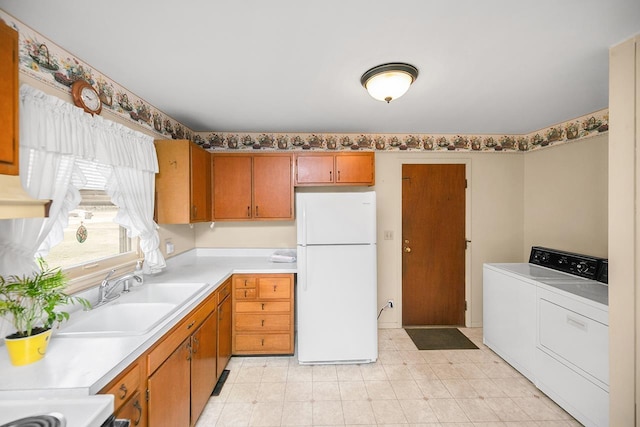 kitchen with brown cabinets, a sink, freestanding refrigerator, separate washer and dryer, and light countertops