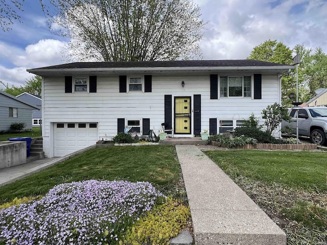 raised ranch featuring an attached garage and a front lawn