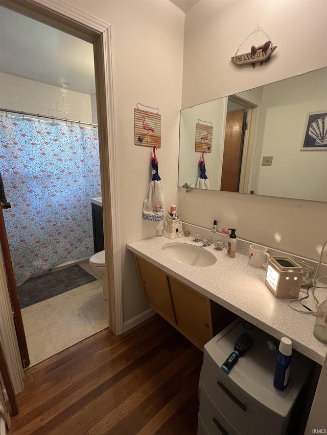 bathroom featuring toilet, a shower with shower curtain, wood finished floors, and vanity