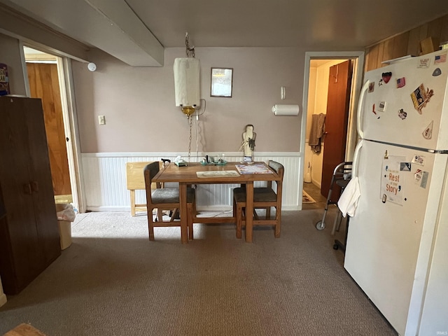 carpeted dining room featuring a wainscoted wall