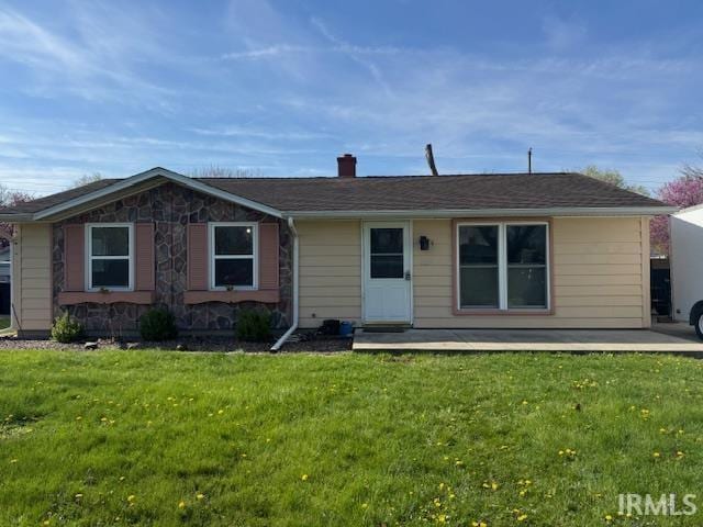 view of front of house featuring stone siding, a chimney, and a front yard