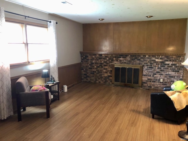 living room featuring a fireplace, light wood-style flooring, a wainscoted wall, and visible vents