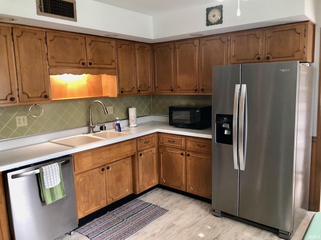 kitchen with a sink, visible vents, decorative backsplash, light countertops, and appliances with stainless steel finishes