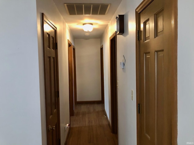 hallway with baseboards, visible vents, and dark wood-style floors