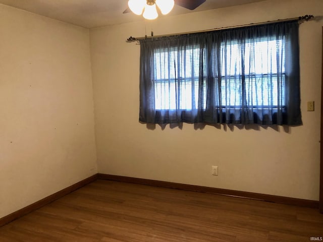 unfurnished room with baseboards, wood finished floors, and a ceiling fan