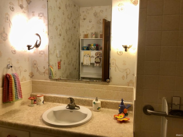 bathroom with wallpapered walls and vanity