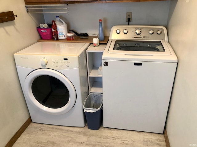 clothes washing area featuring separate washer and dryer and baseboards
