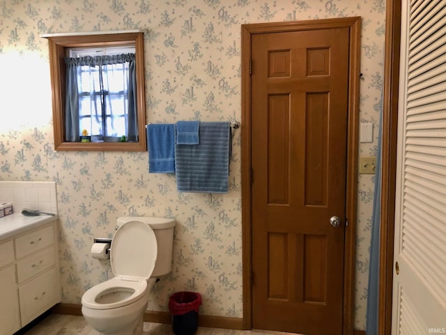 bathroom featuring a closet, toilet, baseboards, and wood finished floors